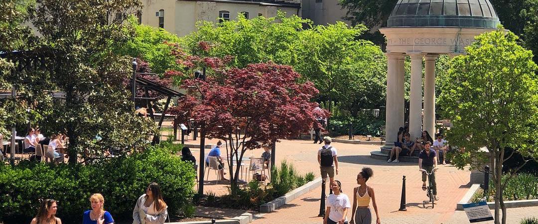 Students walking in Kogan Plaza with the George Washington University tempietto in the background.