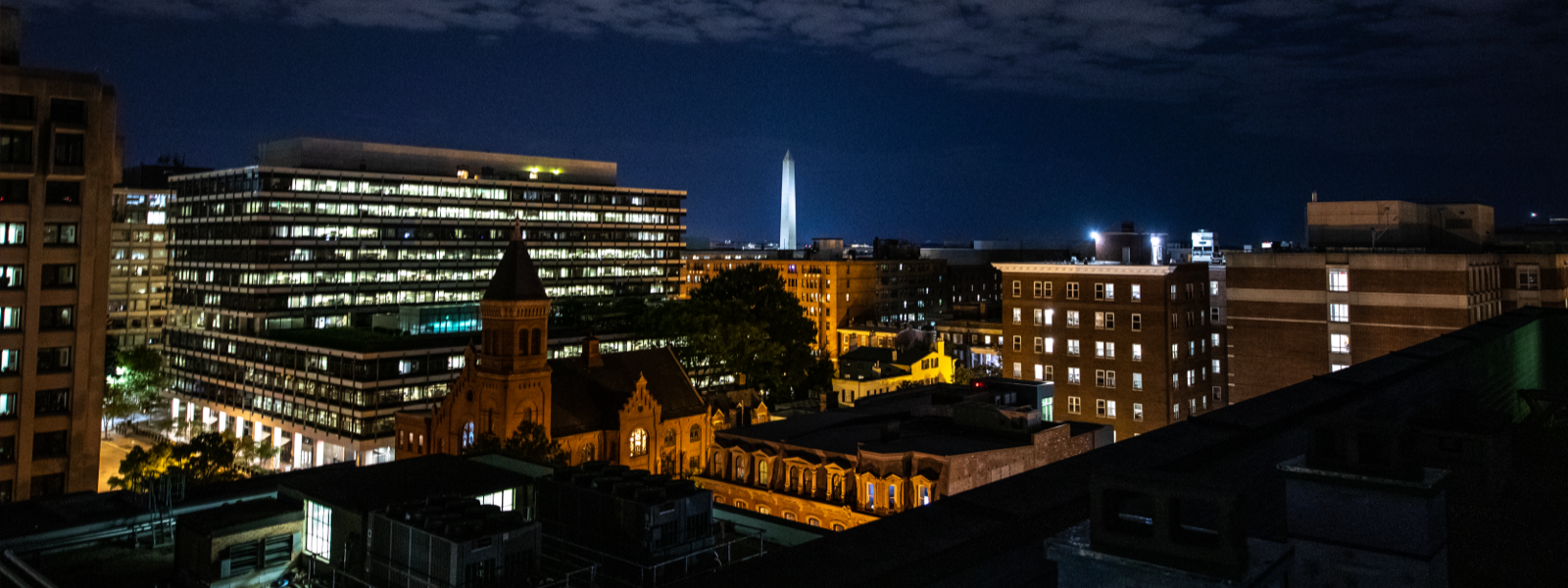 Foggy Bottom at night with the Washington Monument in the background